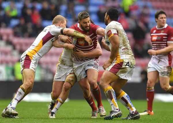 Romain Navarrete drives into the Huddersfield defence and, inset, Tom Davies points to his great-grandads name on the Wigan heritage number list