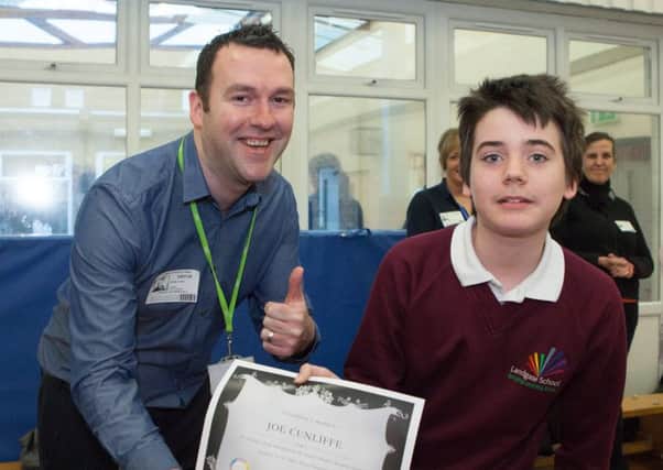 Daniel Dowd, from Wigan Council, hands a certificate to Joe Cunliffe who helped to design the Autism Friends logo