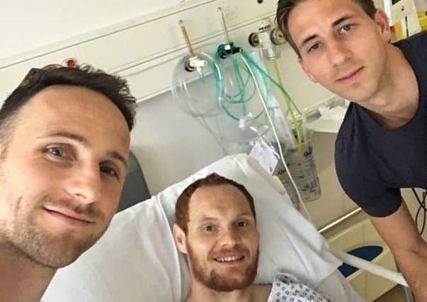 Shaun MacDonald (middle) is visited in hospital by former team-mates