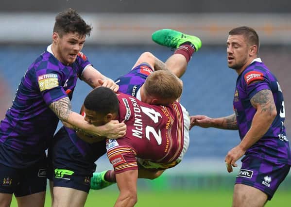 Darnell McIntosh is tackled by Wigan Warriors' Sam Tomkins  and John Bateman