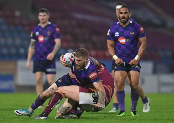 Sam Tomkins is tackled at Huddersfield, watched by Thomas Leuluai