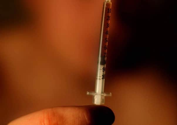 A drug addict holding up a needle before injecting heroin (picture posed)