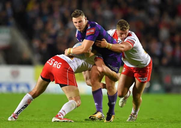 Wigan Warriors' George Williams is tackled by St Helens' Luke Douglas and Morgan Knowles