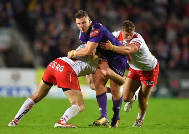 Wigan Warriors' George Williams is tackled by St Helens' Luke Douglas  and Morgan Knowles