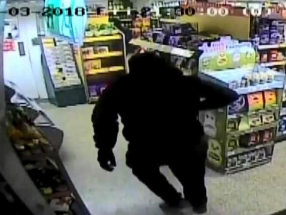 One of the robbers enters the store