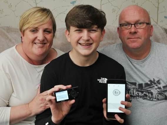 Vinny Patterson with mum and dad Sam and Mark, and his Dexcom G5 Mobile device, which regularly checks glucose levels and alerts him and his parents if there are any issues